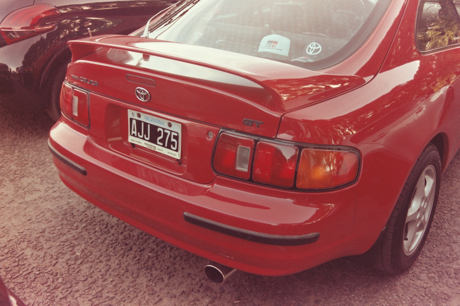 a red car parked in a parking lot next to other cars