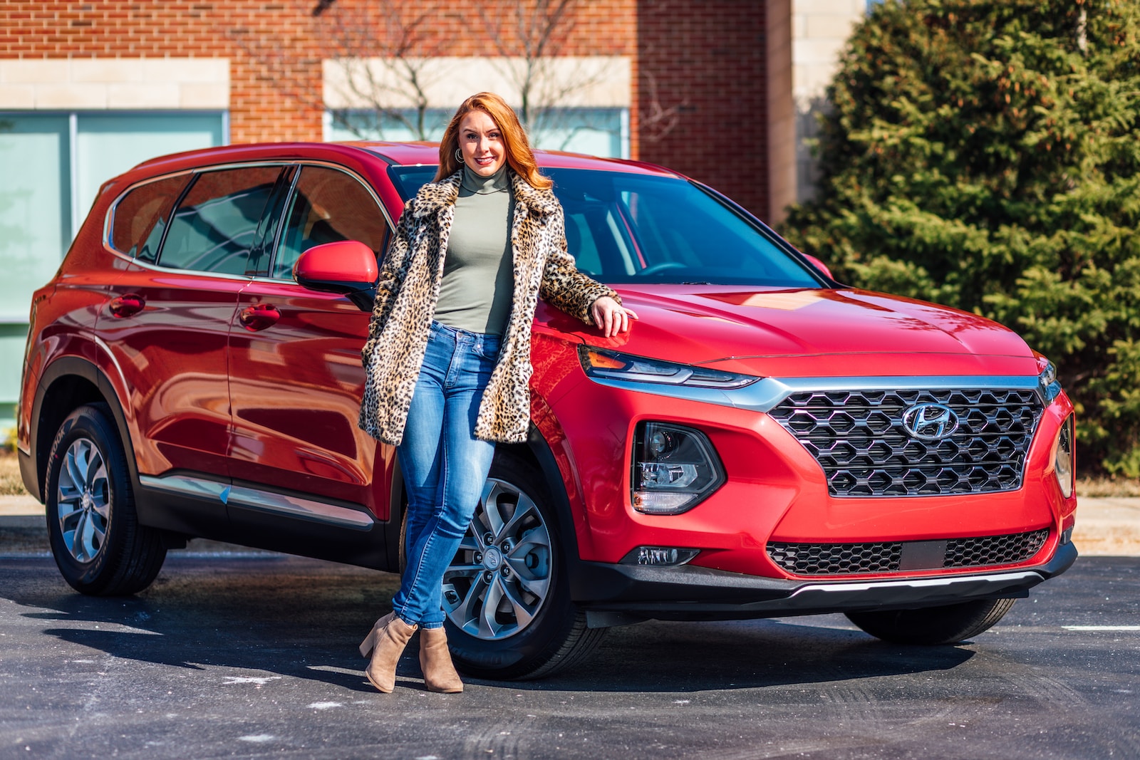 woman in white and black scarf and blue denim jeans standing beside red mercedes benz car