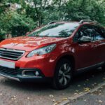 red Peugeot SUV parked beside curb