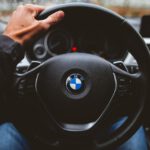 person holding BMW vehicle steering wheel