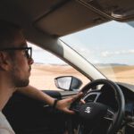 man in white shirt driving car during daytime