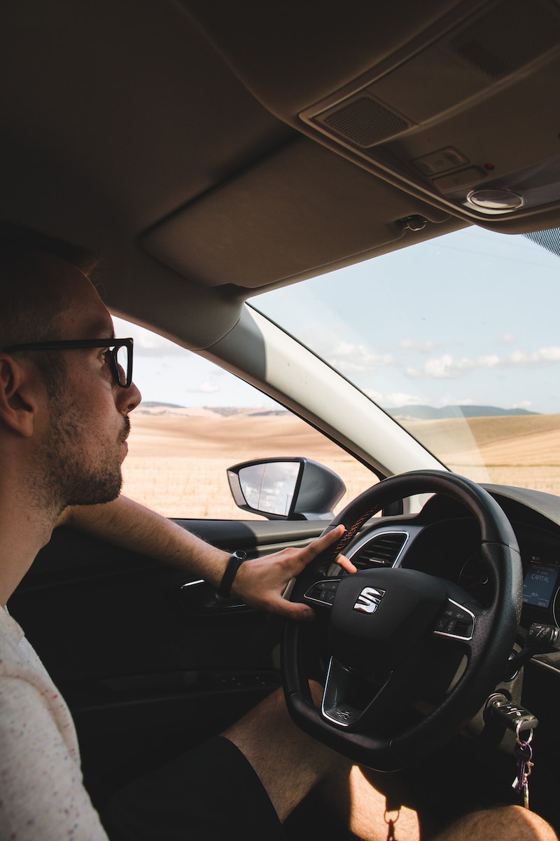 man in white shirt driving car during daytime