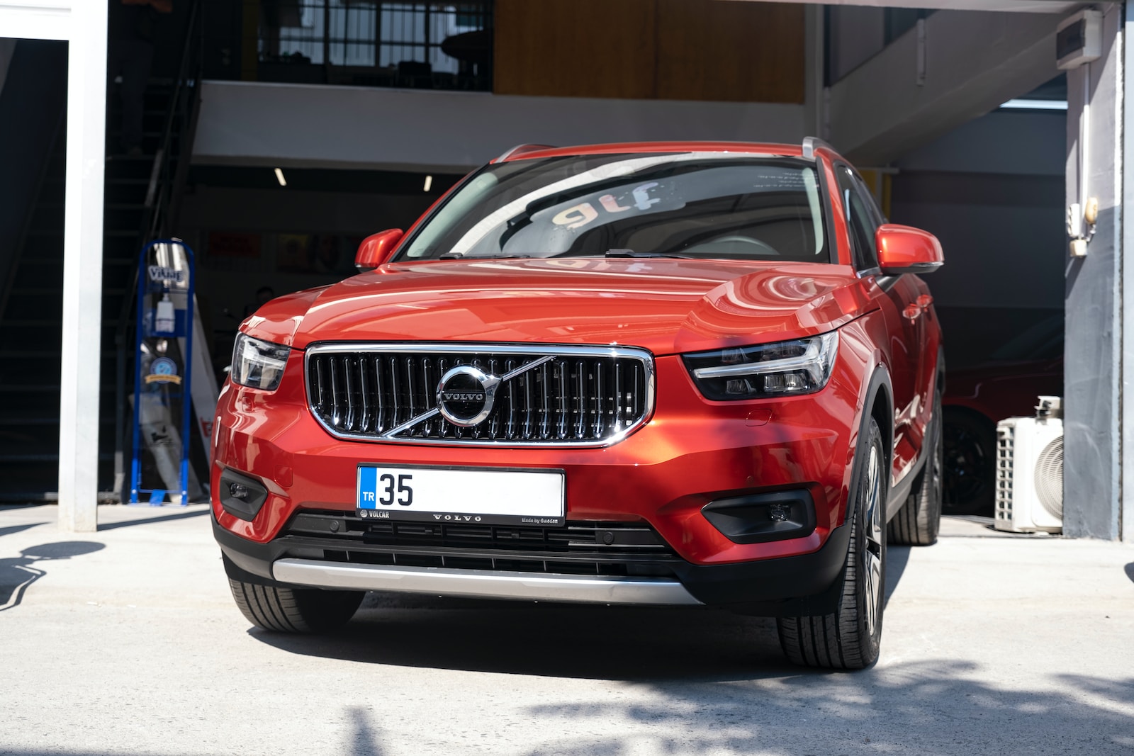 a red volvo car parked in front of a garage