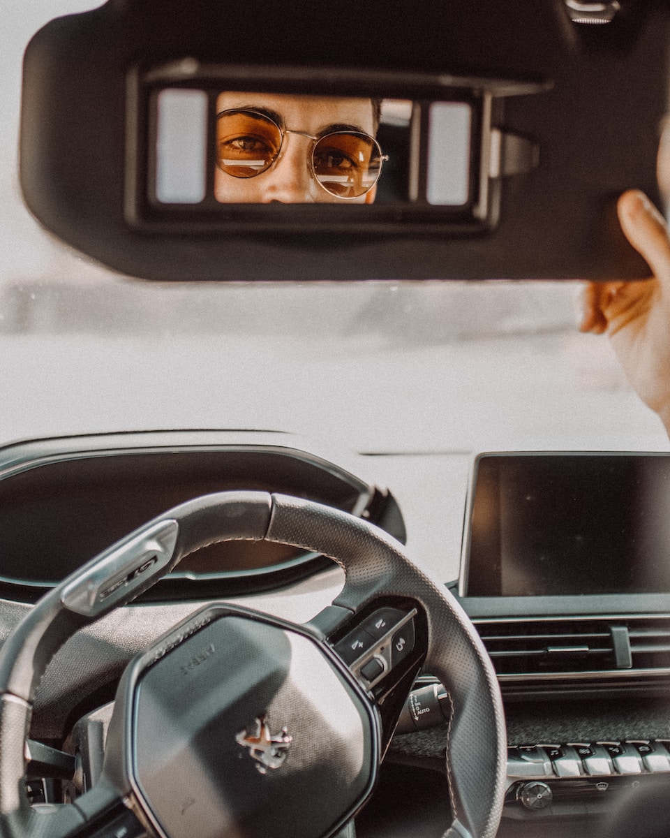 man looking through Peugeot vehicle sun shade's mirror