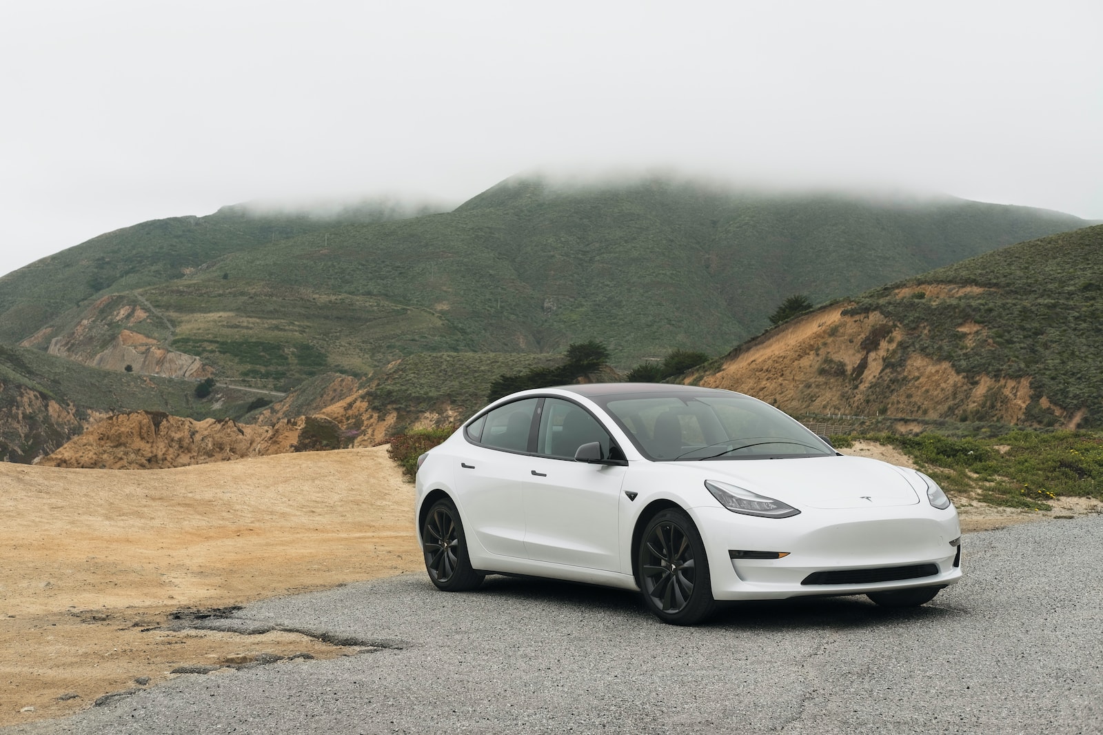 white sedan parked beside mountain during daytime