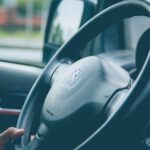 a steering wheel of a car with a hand on the steering wheel