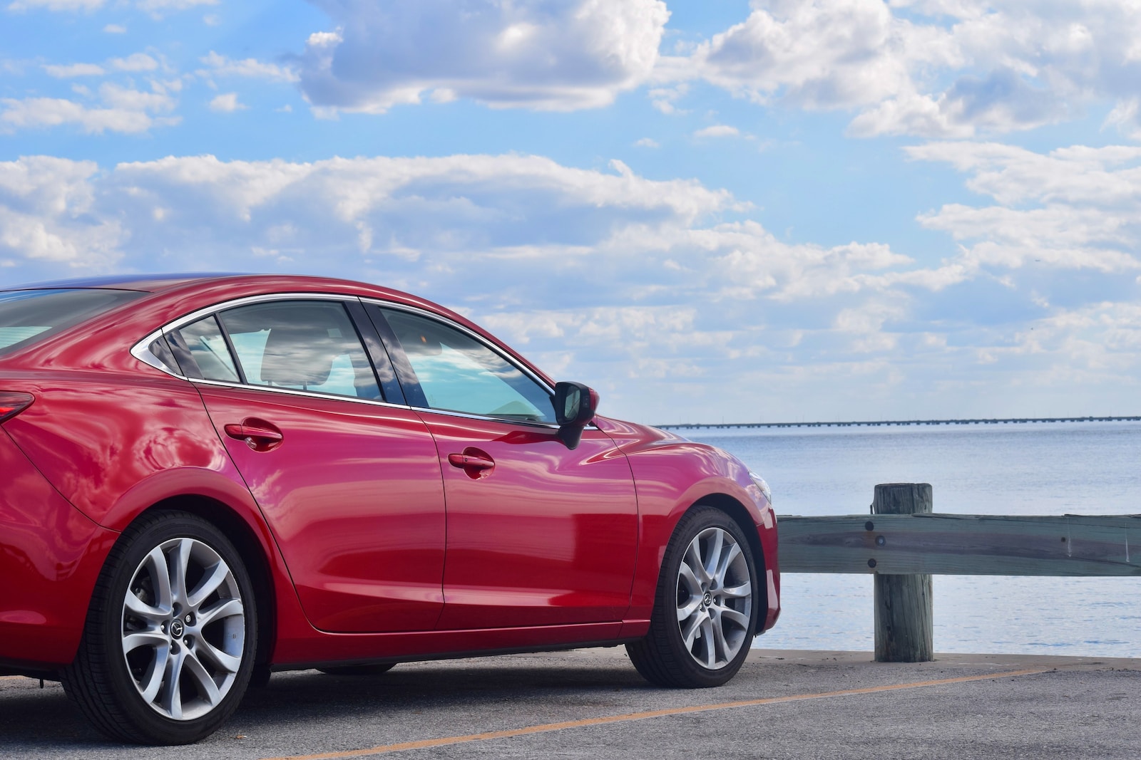 a red car parked on a road by the water