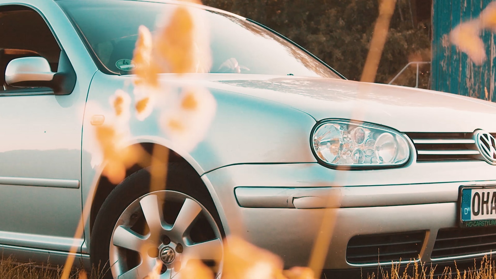 a silver car parked in a field of tall grass