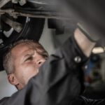 a man working on a car under a vehicle