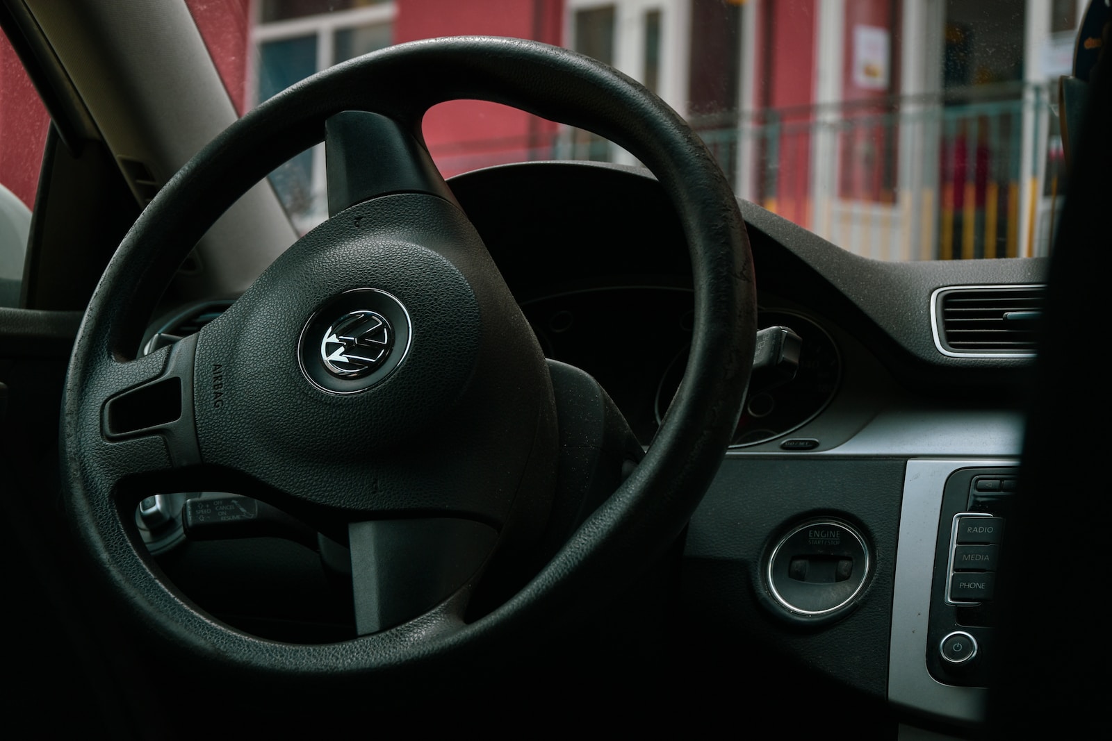 a steering wheel of a car with a red building in the background