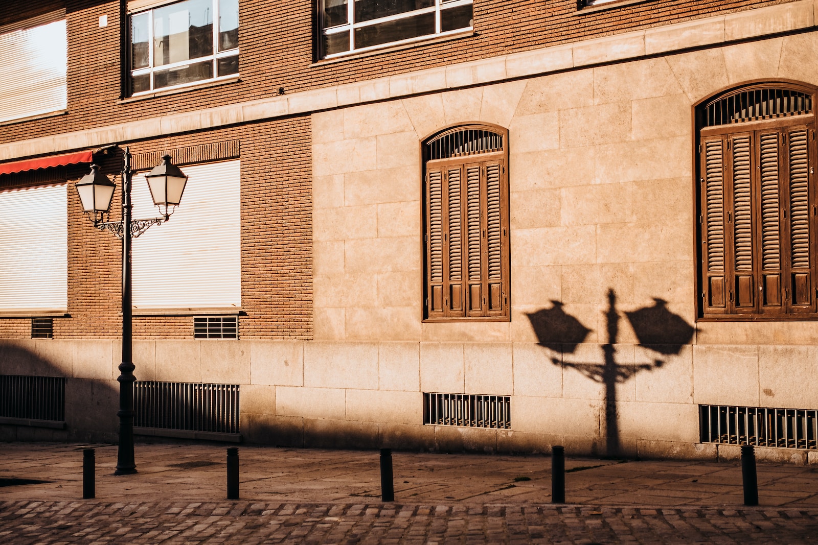 shadow of lamp post beside building during daytime