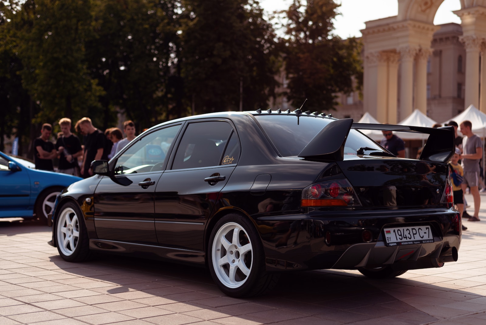 a car parked in front of a building with people standing around