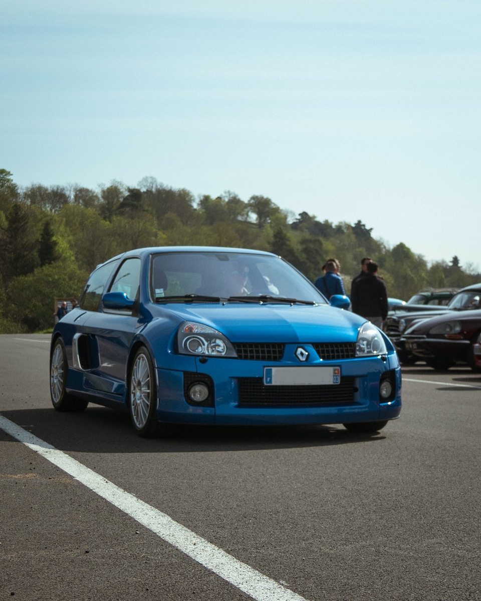 a blue car parked in a parking lot with other cars