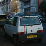 a small white car parked on the side of the road