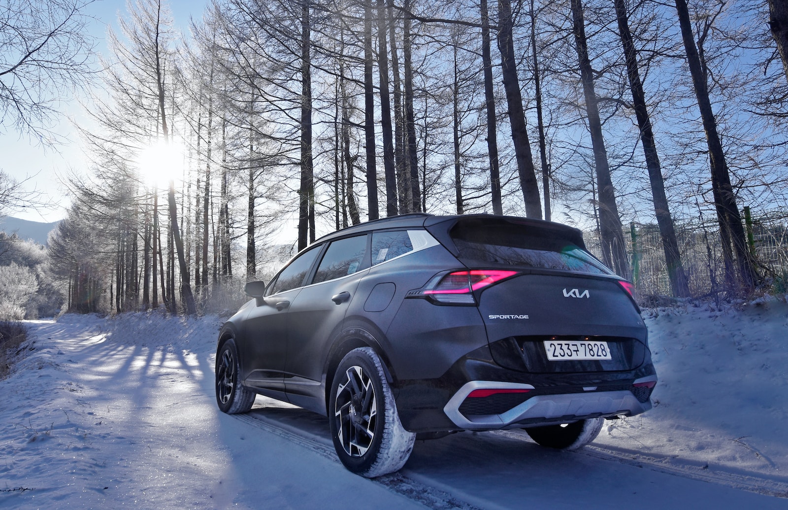 a black car driving down a snow covered road