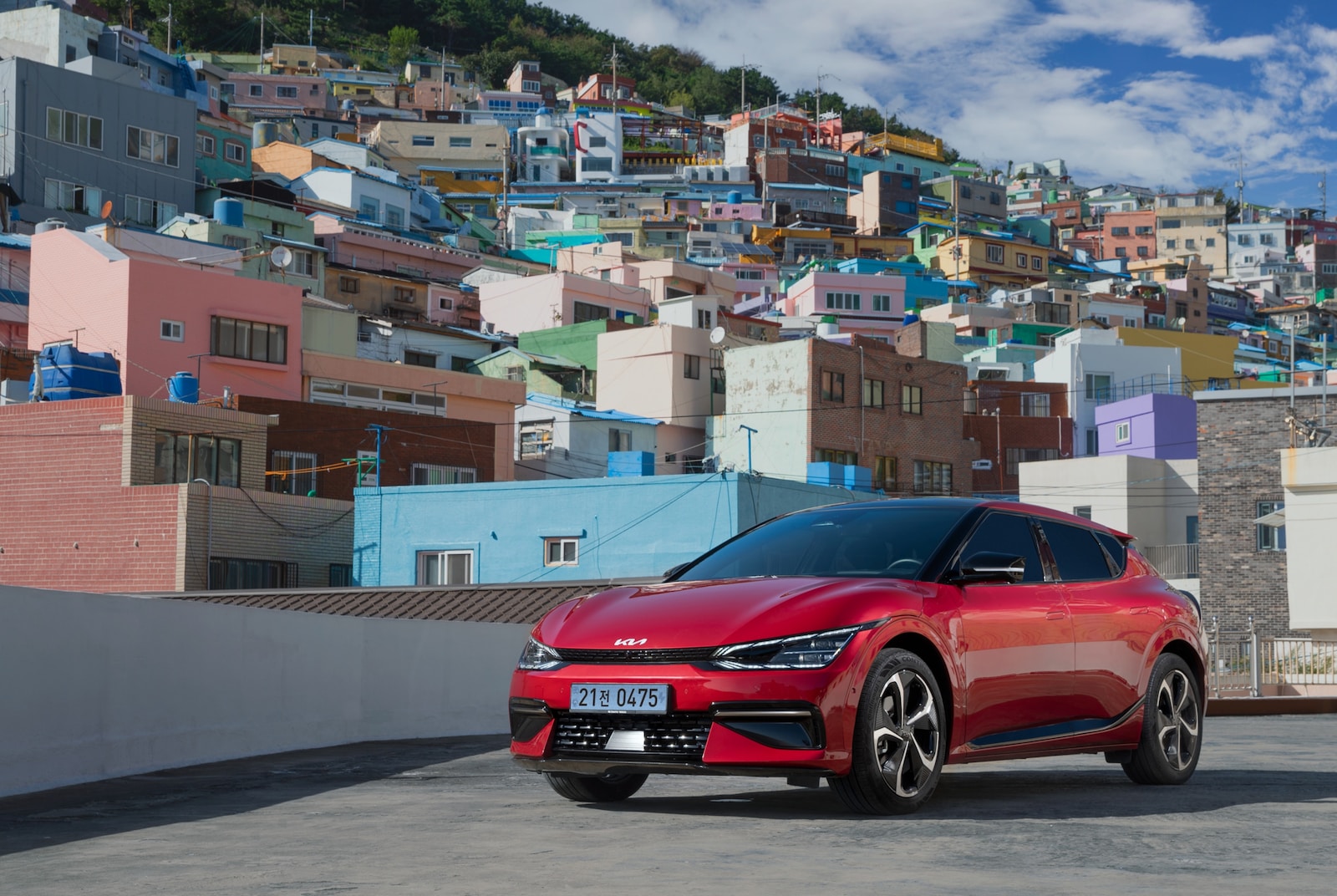 a red car parked on a road with buildings in the background